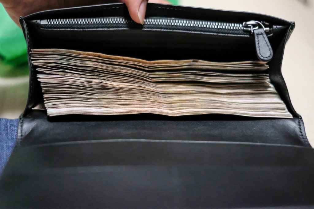 17 Bills Worth More Than Face Value Hiding in Your Wallet Right Now – Spot Them Easily Black wallet full of money indicative of bill worth more than face value.