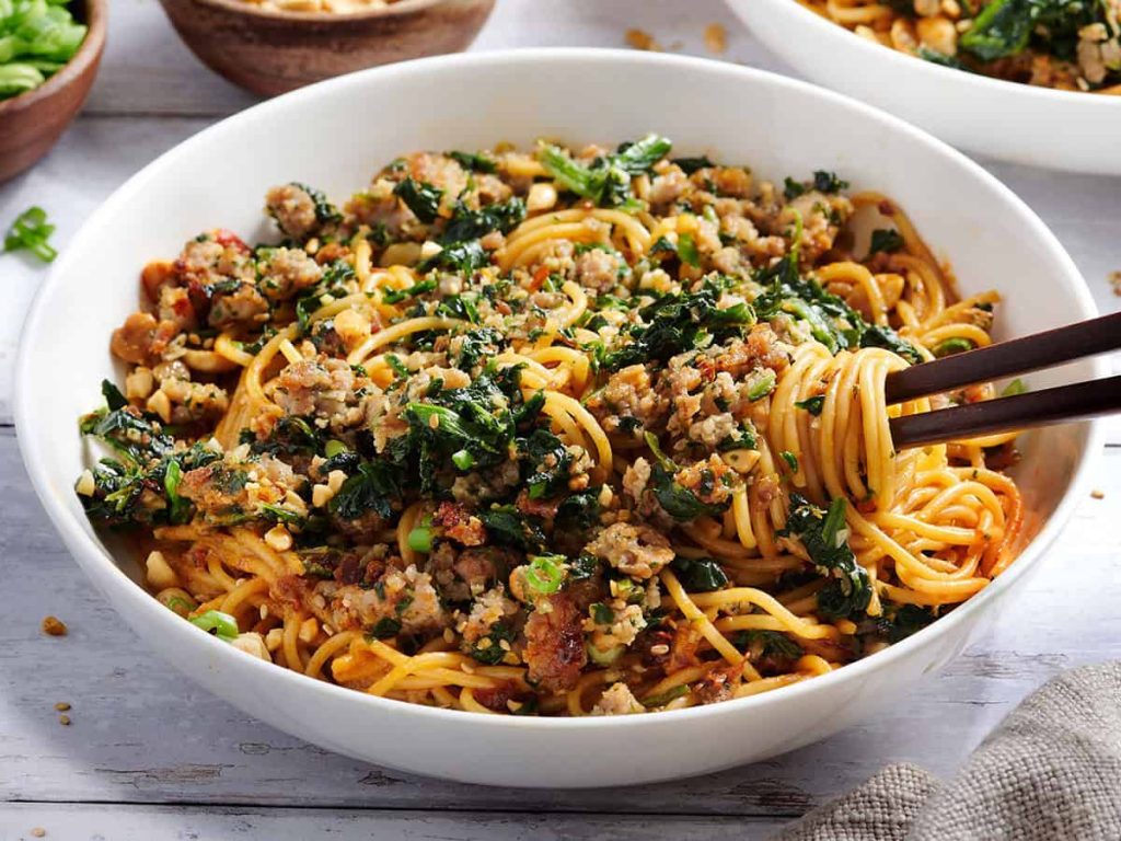 Side view of a bowl of dan dan noodles with chopsticks.Overhead view of a bowl of dan dan noodles with chopsticks.