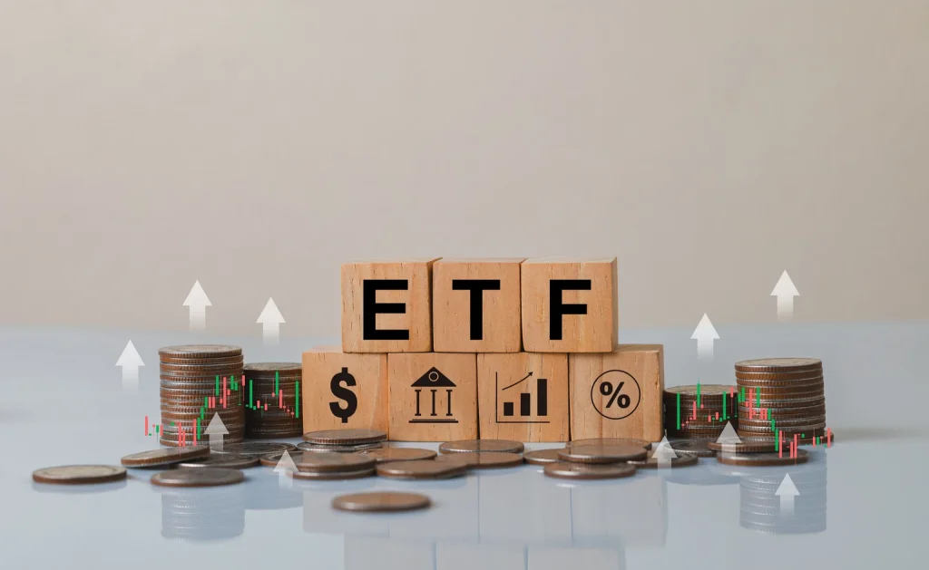 Wooden Blocks with ETF Letters Surrounded by Coins and Financial Icons Representing Investment Growth and Financial Strategies in a Modern Finance Context