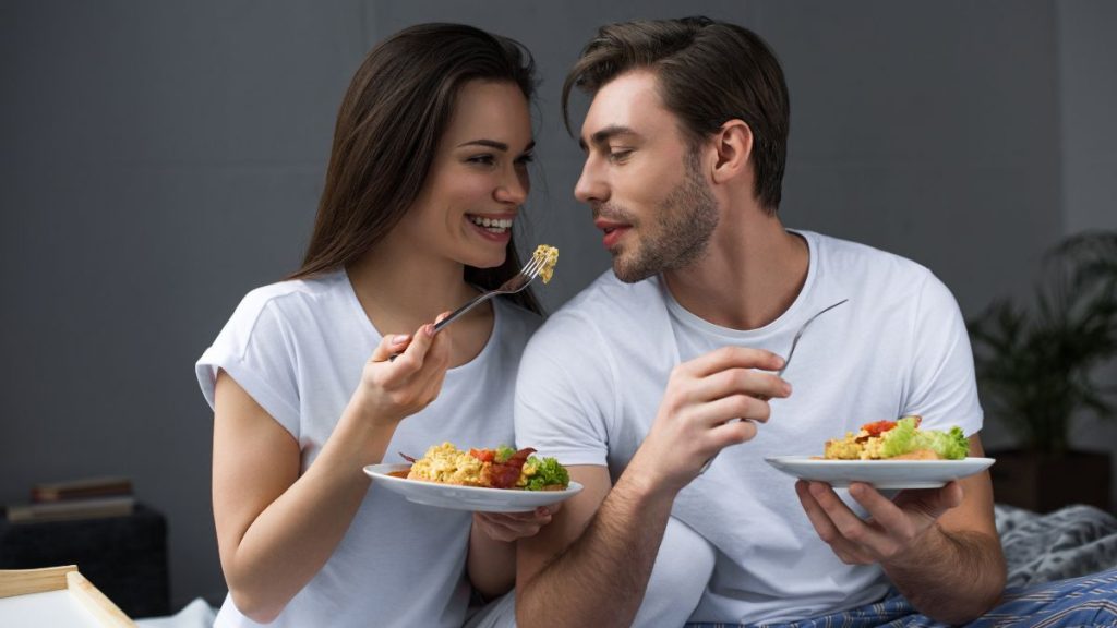 Couple sweetly having eggs for breakfast on bed MSN