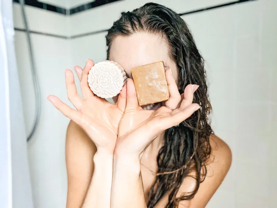 Clean Series: 4 Best Toxic Free & Clean Hair Products woman holding bar shampoo and conditioner in shower in front of face