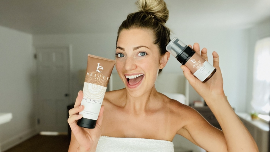 You’ll Never Use Any Other Self Tanner After Reading This! a woman smiling and holding bottle of self tanner