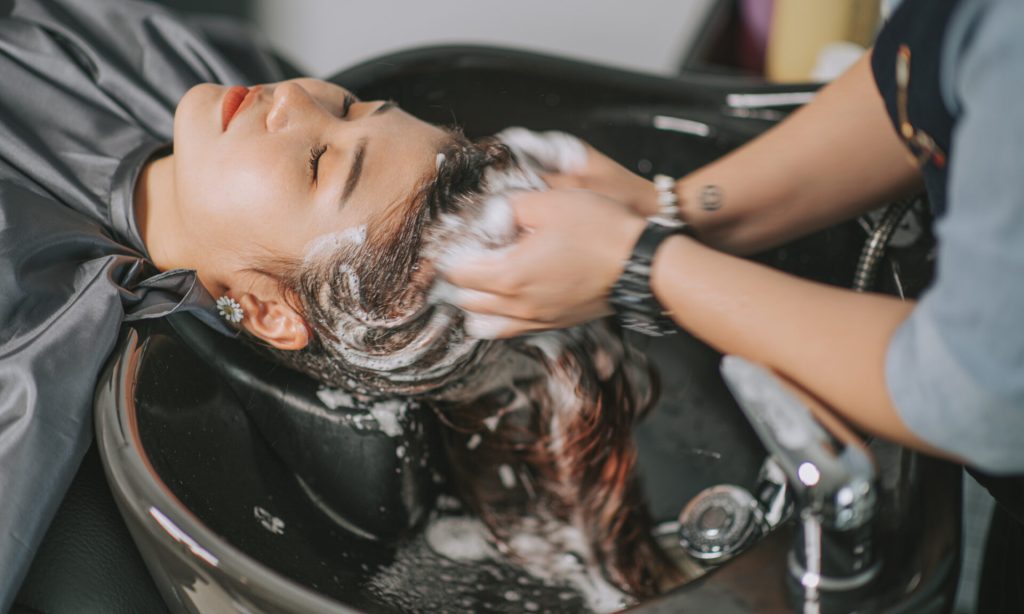 Directly above Asian chinese female lying down for hair wash at hair salon with eyes closed