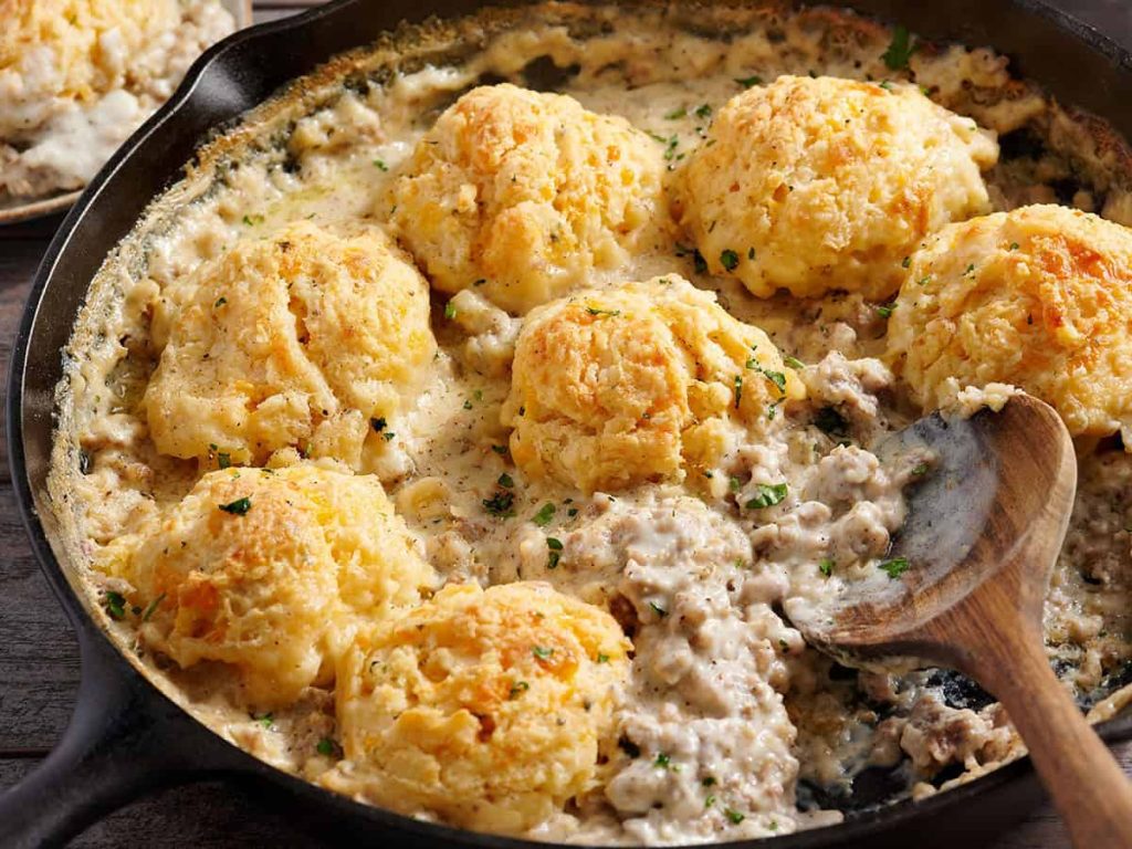 Biscuits and Gravy Bake – Budget Bytes Side view of a biscuit and gravy bake in a skillet with a wooden spoon.