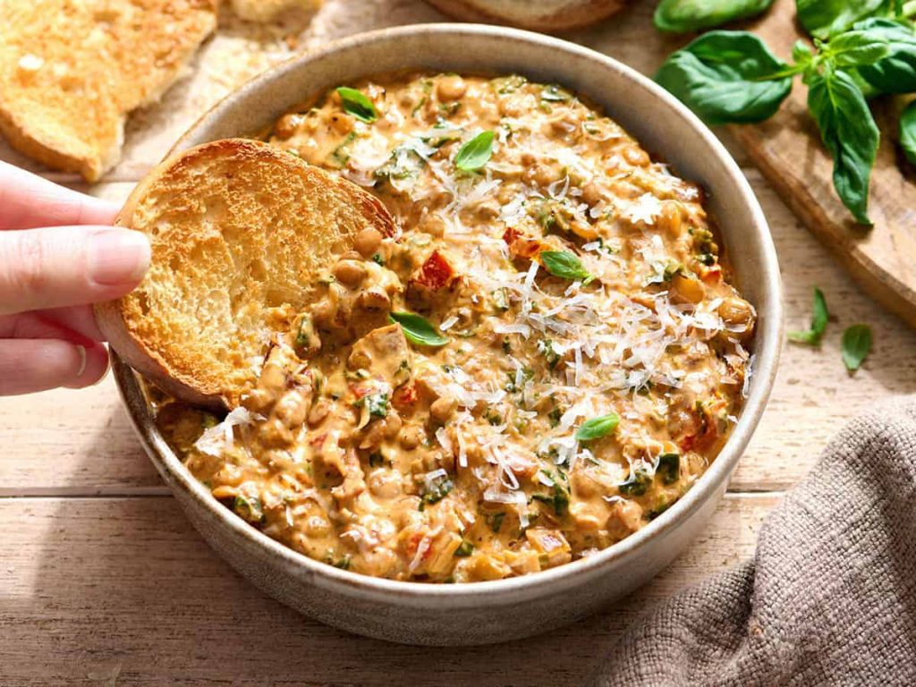 Creamy Marry Me Lentils – Budget Bytes A hand dipping a slice of toasted bread in a bowl of marry me lentils.