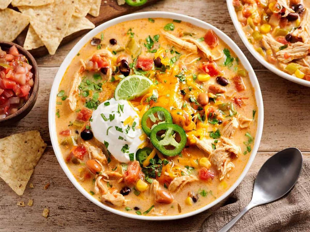 Overhead close up of chicken taco soup in a bowl topped with jalapeno slices and sour cream.
