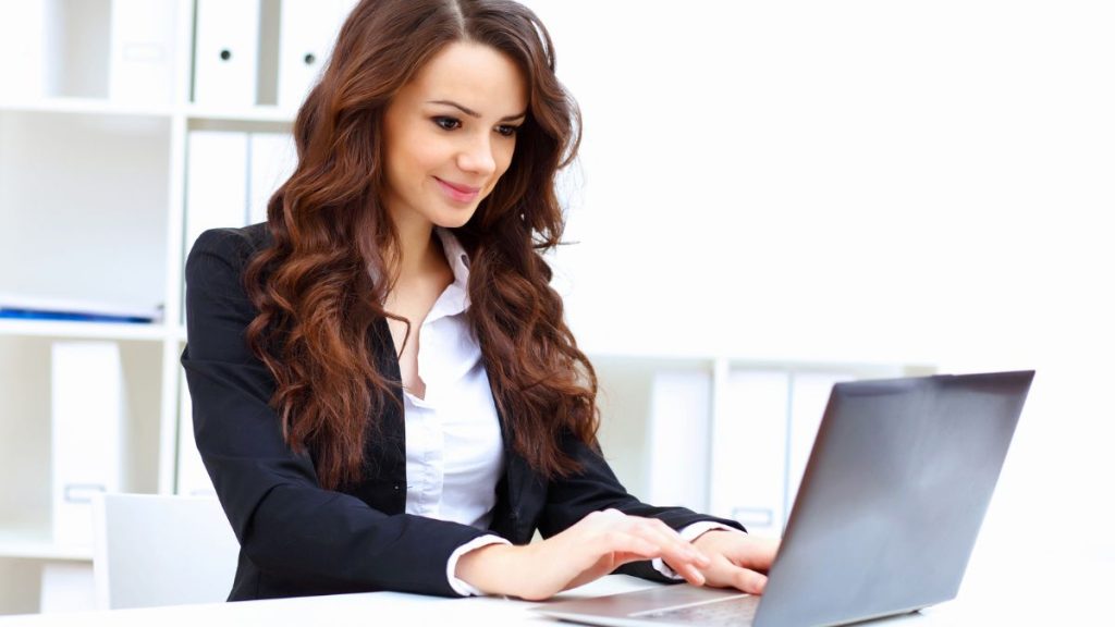 Woman Smiling While Using A Laptop