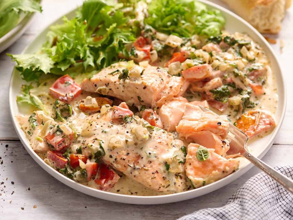 Side view of Tuscan salmon on a plate with salad.